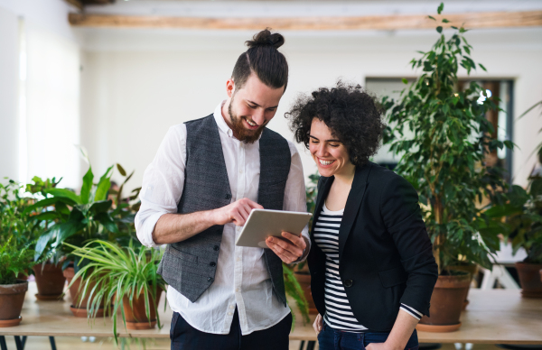 Two young businesspeople using a tablet in office, start-up concept.