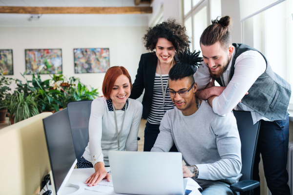 A group of young businesspeople with laptop working in office, start-up concept.