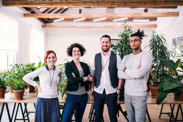 A group of young businesspeople standing in office, looking at camera.