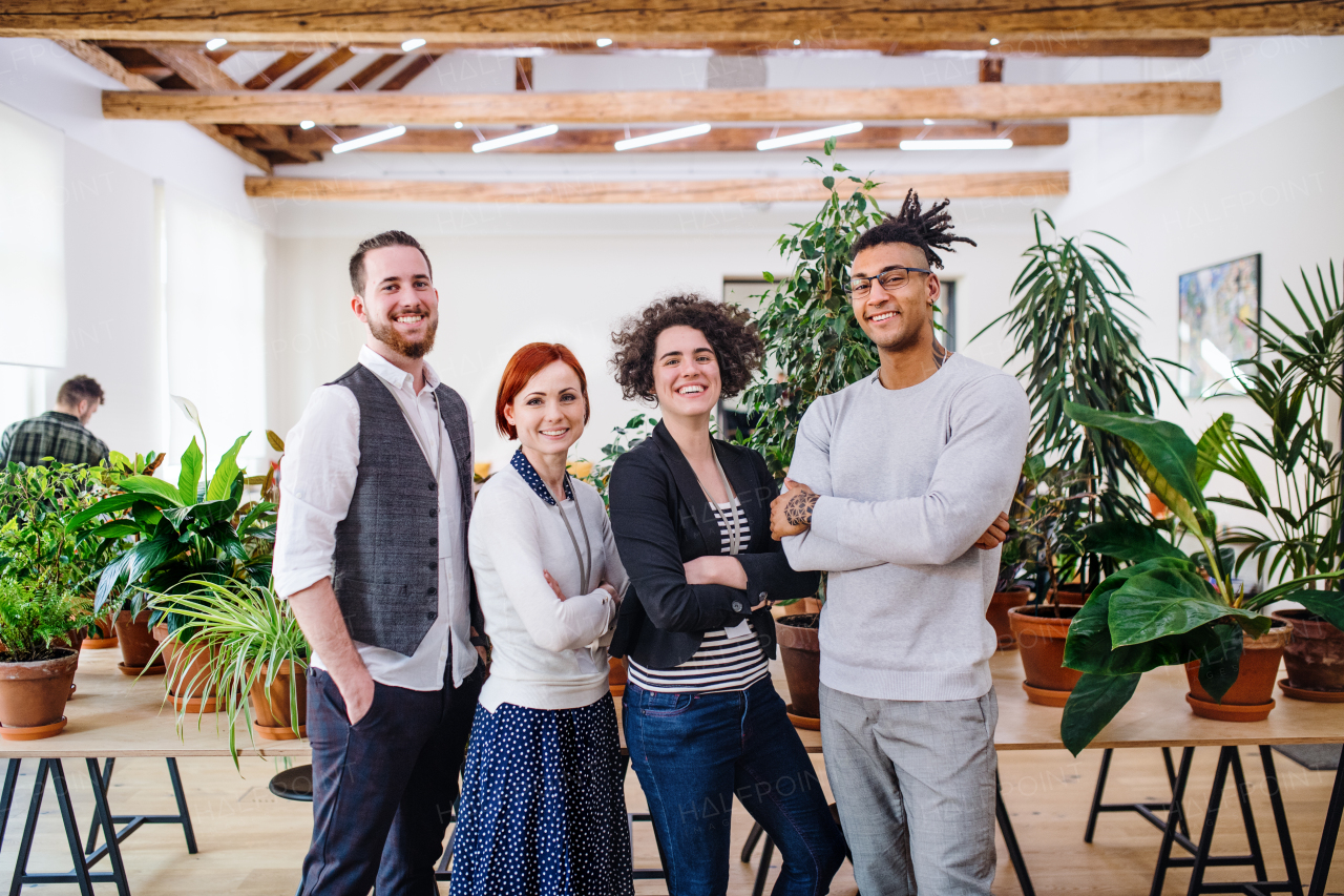 Portrait of group of young businesspeople standing in office, looking at camera.