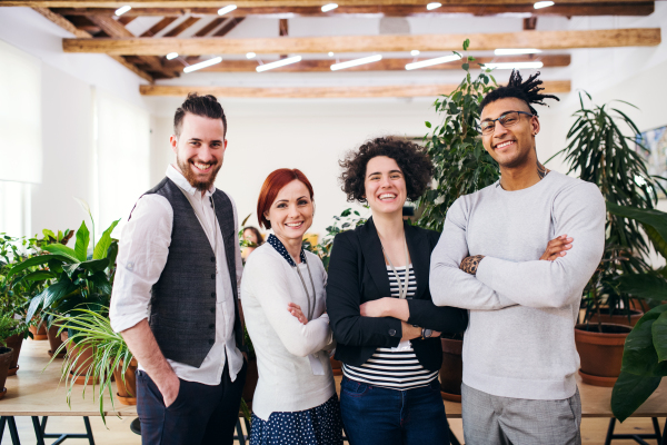 Portrait of group of young businesspeople standing in office, looking at camera.