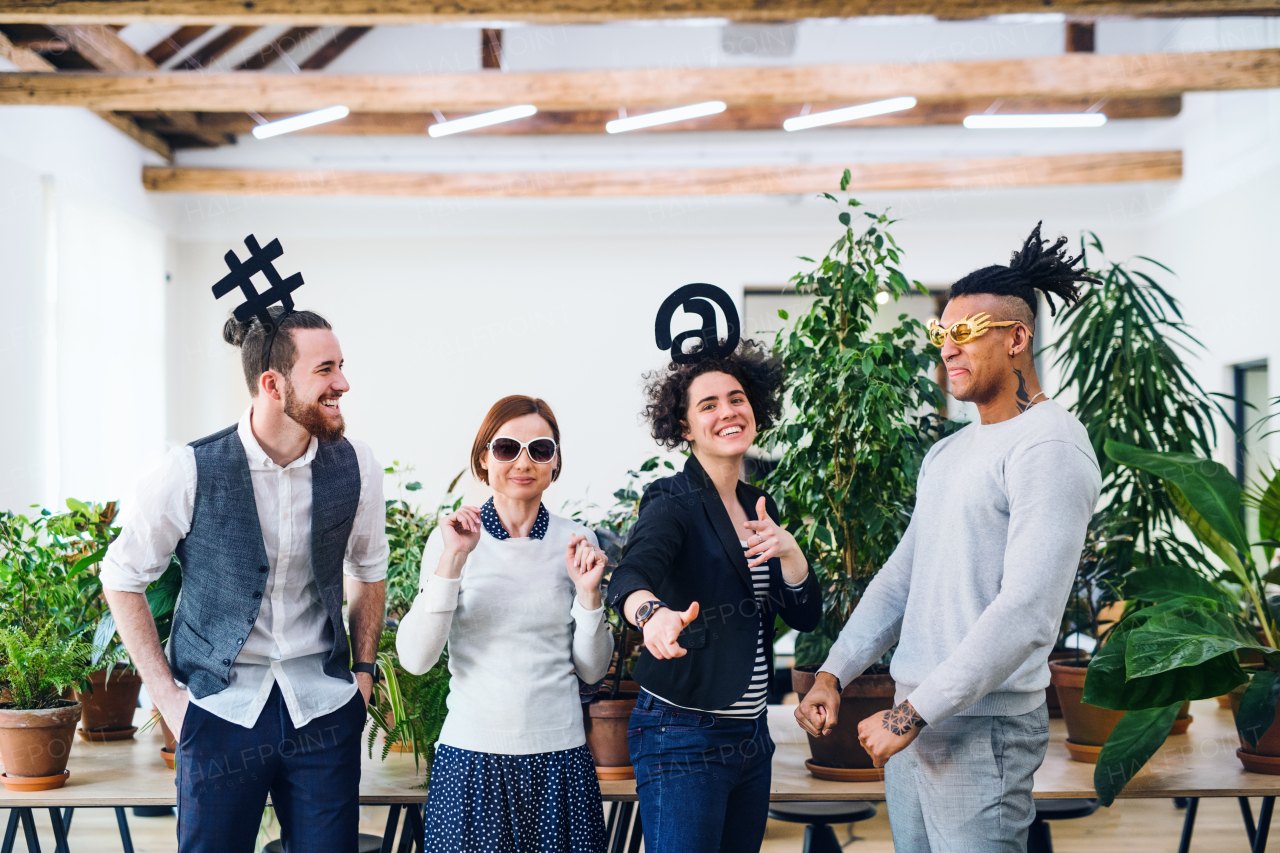 Portrait of group of young businesspeople standing in office, having fun on party.