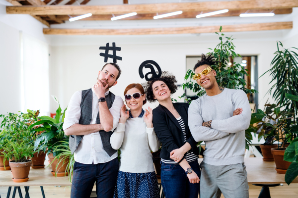 Portrait of group of young businesspeople standing in office, having fun on party.