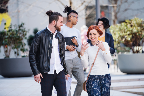 Group of young businesspeople walking outdoors in courtyard, talking. A start-up concept.