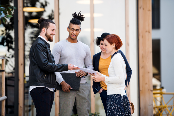 Group of young businesspeople standing outdoors in courtyard, talking. A start-up concept.