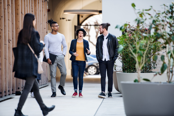 Group of young businesspeople walking outdoors in courtyard, talking. A start-up concept.