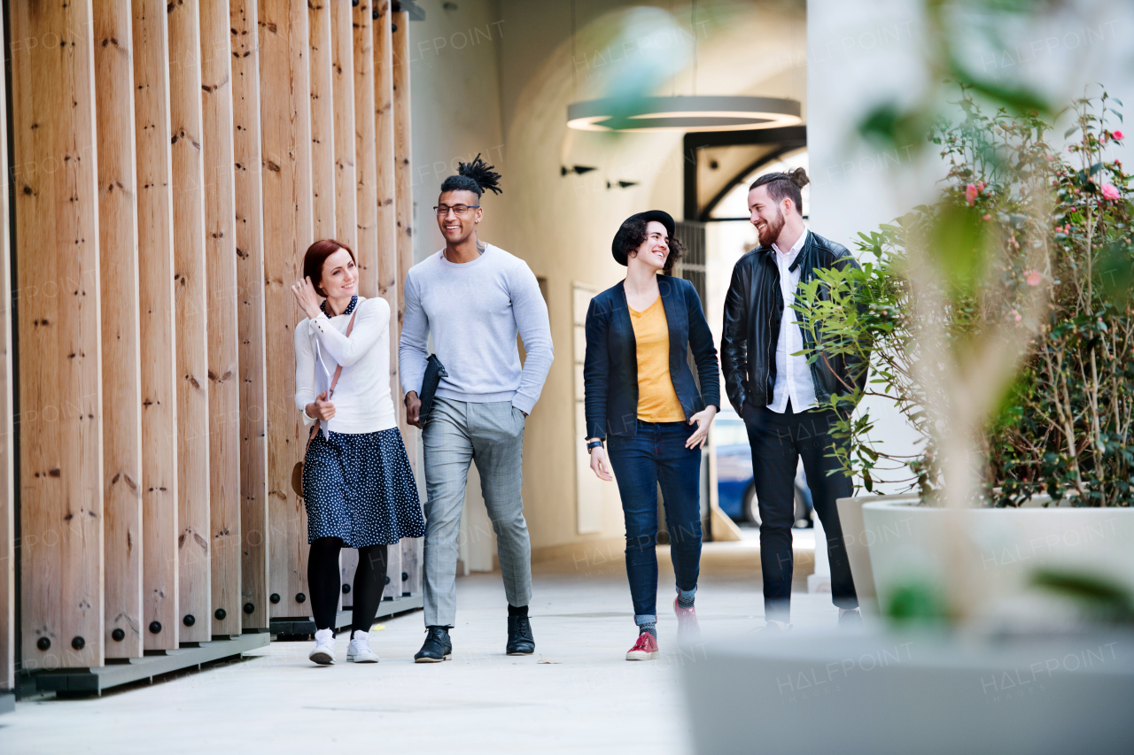 Group of young businesspeople walking outdoors in courtyard, talking. A start-up concept.