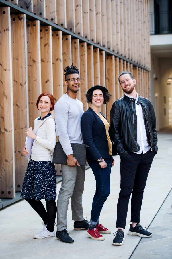 Group of young businesspeople standing outdoors in courtyard, having fun. A start-up concept.