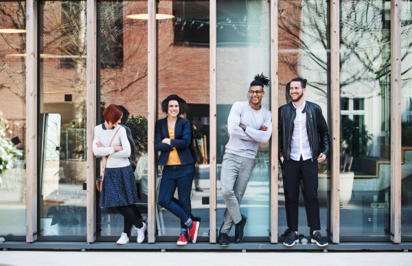 Group of young businesspeople standing outdoors in courtyard, arms crossed. A start-up concept.