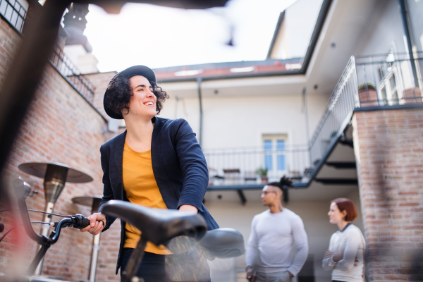 A happy young business woman with bicycle standing outdoors. Start-up concept.