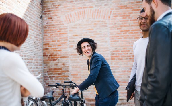 Group of young businesspeople with bicycle outdoors in courtyard, talking. A start-up concept.