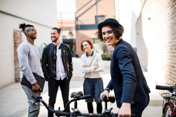 A happy young business people with bicycle standing outdoors. Start-up concept.