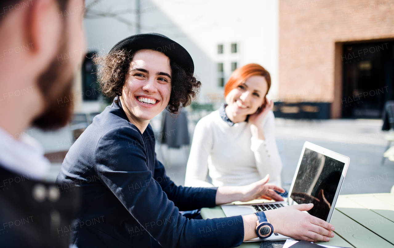 Young businesspeople with laptop outdoors in courtyard, laughing. Start-up concept.