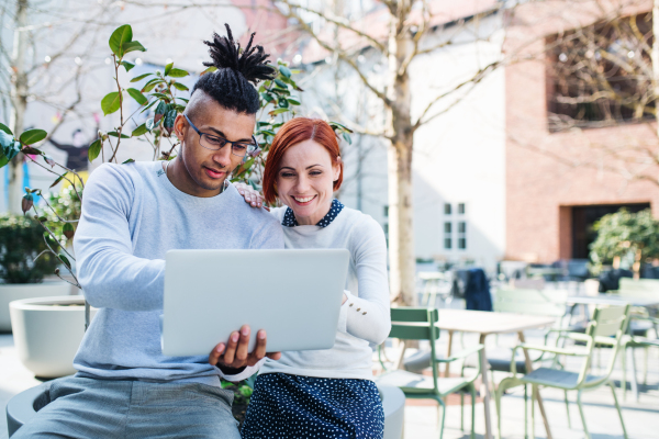 Young businesspeople with laptop outdoors in courtyard, talking. Start-up concept.