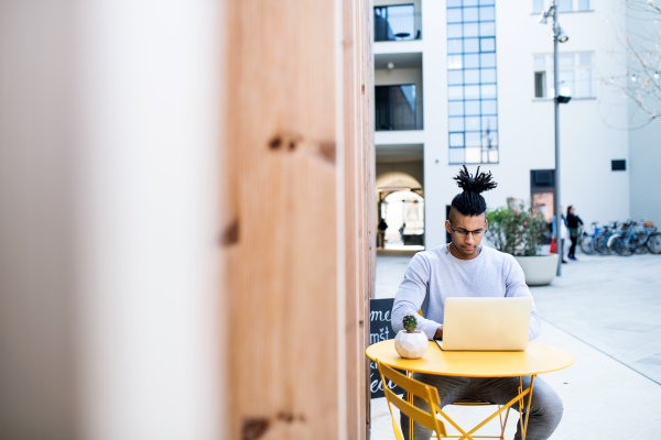 Young businessman with laptop outdoors in courtyard, talking. Start-up concept. Copy space.