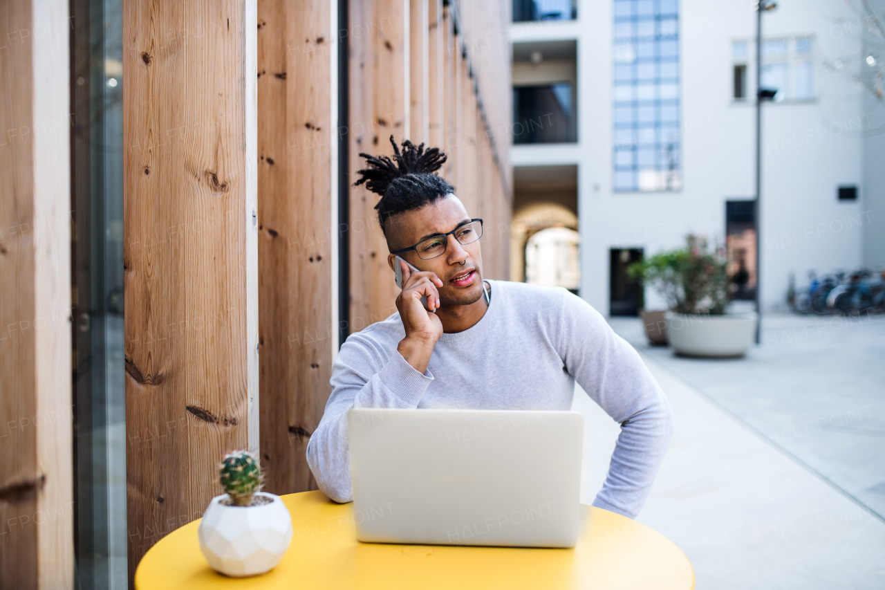 Young businessman with laptop outdoors in courtyard, talking. Start-up concept. Copy space.