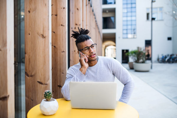 Young businessman with laptop outdoors in courtyard, talking. Start-up concept. Copy space.