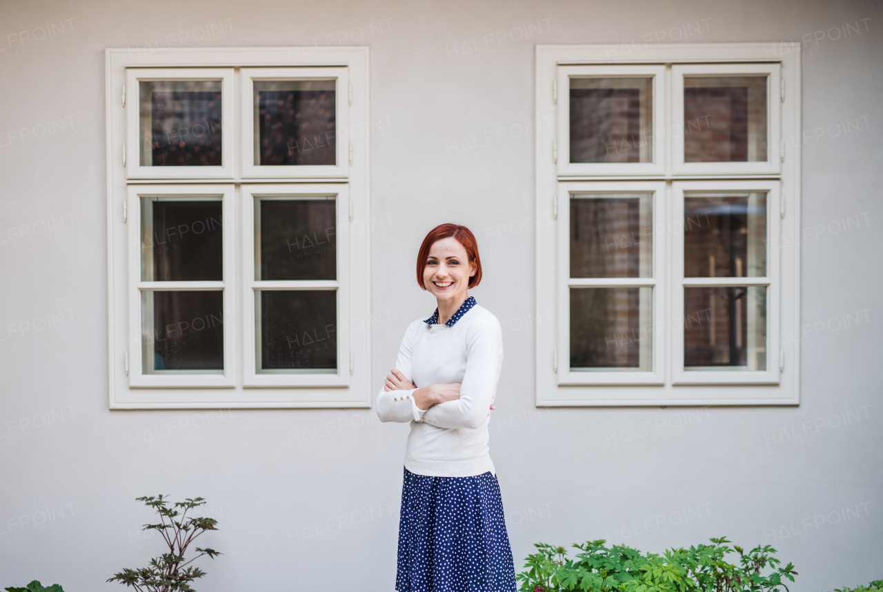 A portrait of young business woman standing outdoors, arms crossed. Start-up concept.