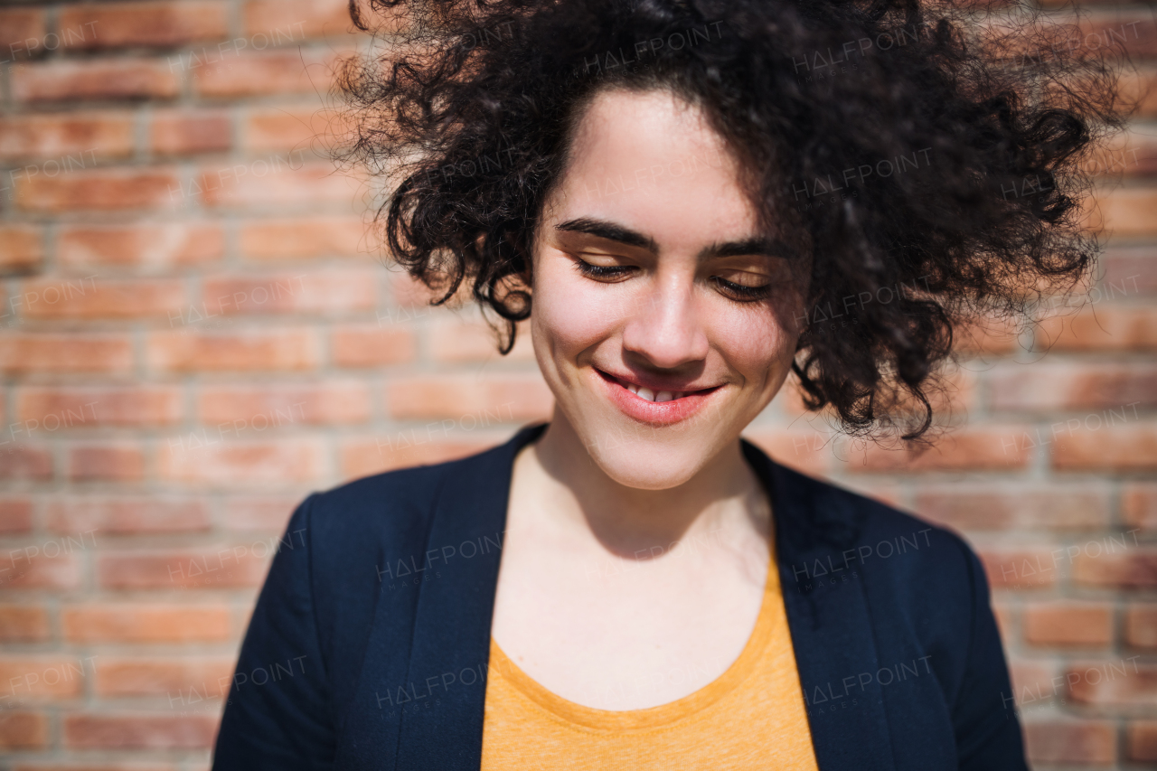 A happy young business woman standing outdoors, brick wall in the background. Start-up concept.