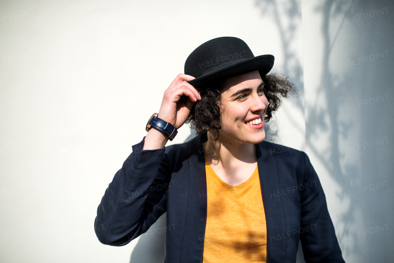 A happy young business woman standing outdoors, holding hat. Start-up concept.