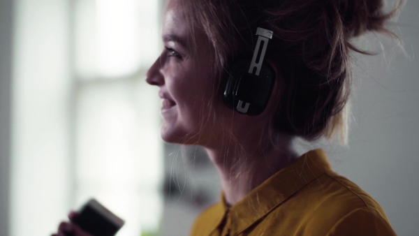 A young female student with headphones and telephone having a break when studying, dancing.