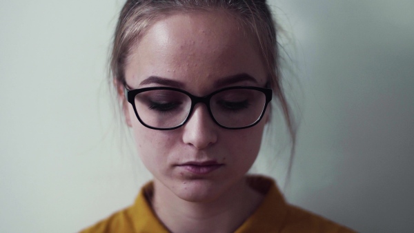 A front view portrait of young sad girl looking at camera, a close-up.