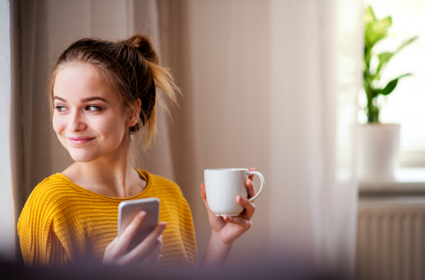 A young female student with coffee and smartphone resting. Copy space.