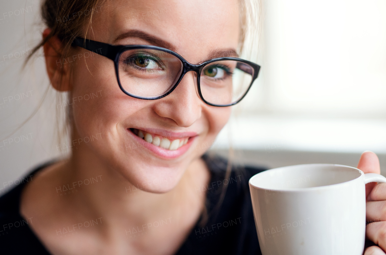 A close-up portrait of happy young female student, holding cup of coffee.