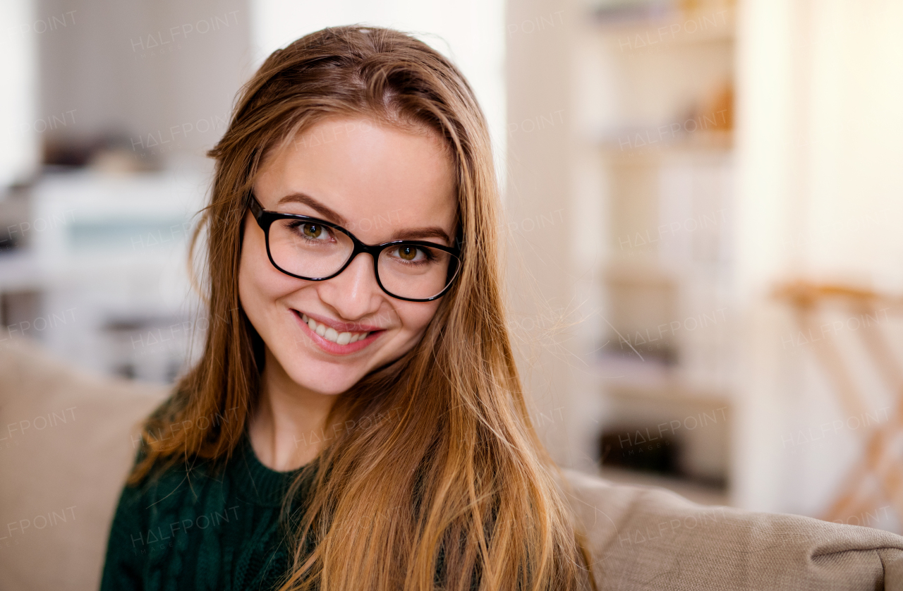 A close-up portrait of happy young female student sitting indoors.