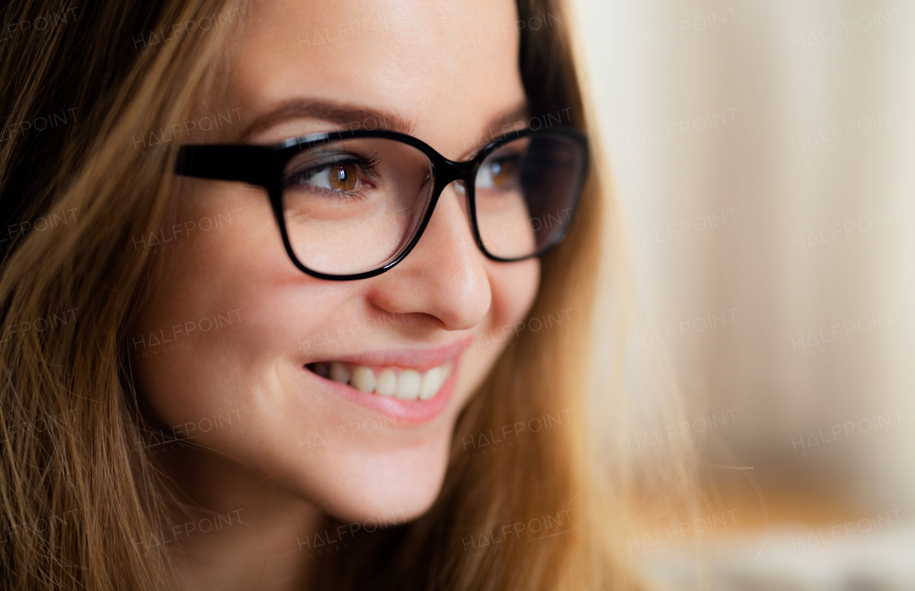 A close-up portrait of happy young female student standing indoors.