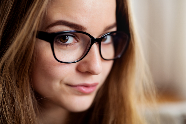 A close-up portrait of happy young female student standing indoors.