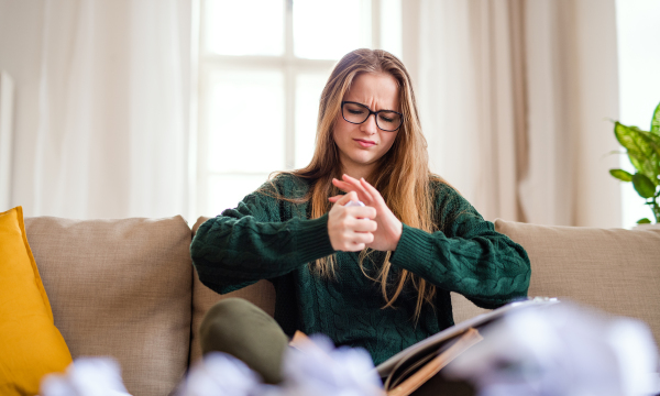 An unhappy, sad and frustrated female student sitting on sofa, studying.