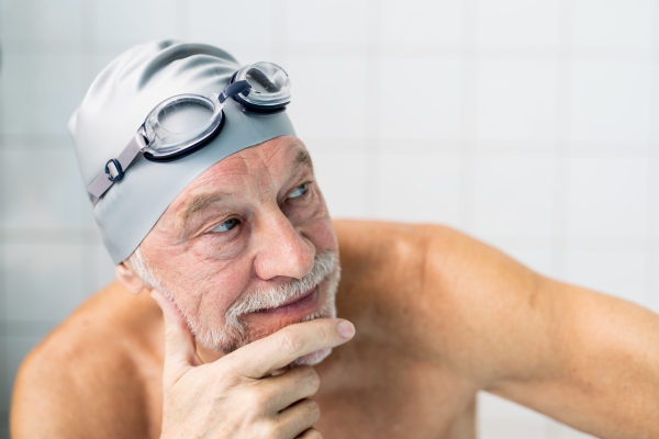 Portrait of a senior man in an indoor swimming pool. Active pensioner enjoying sport. Close up.