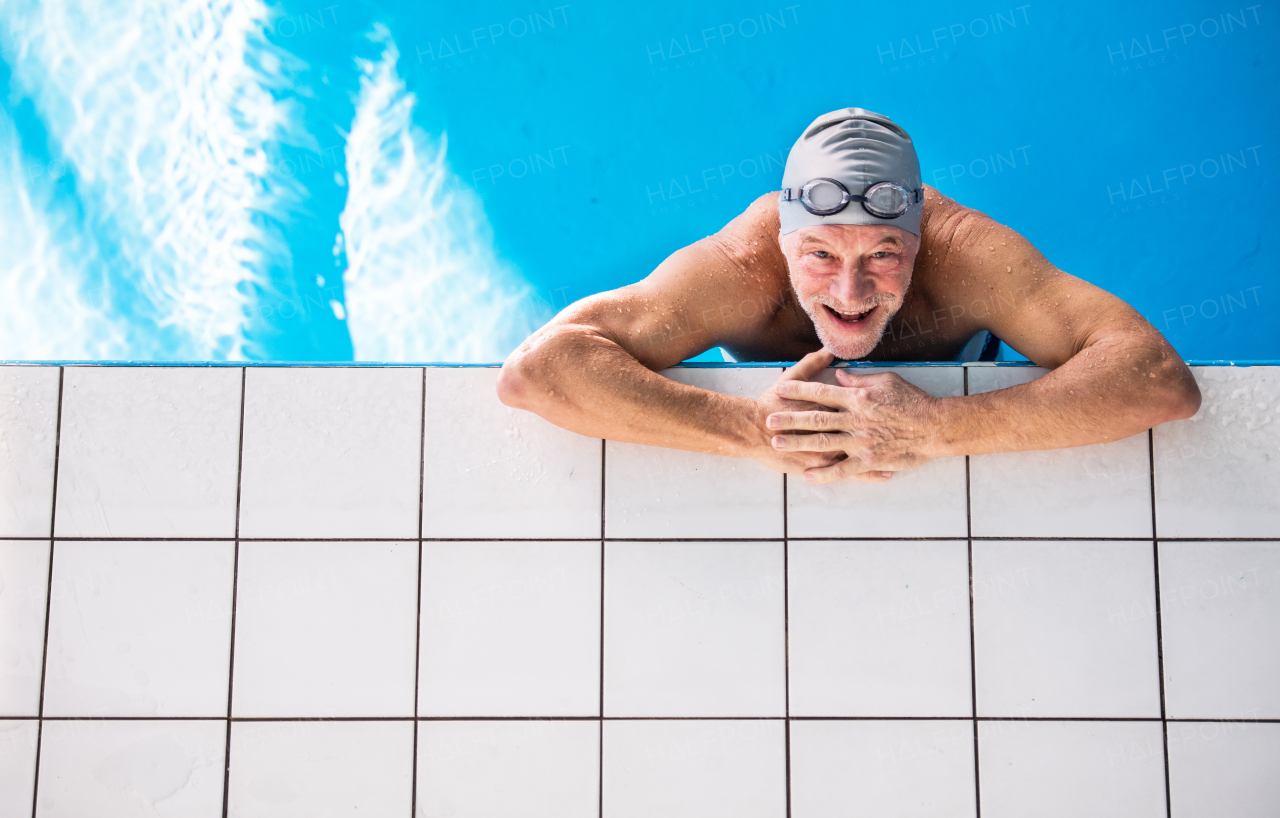 Senior man in an indoor swimming pool. Active pensioner enjoying sport. Top view.