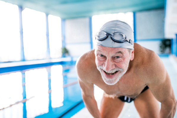 Senior man in an indoor swimming pool. Active pensioner enjoying sport. Close up.