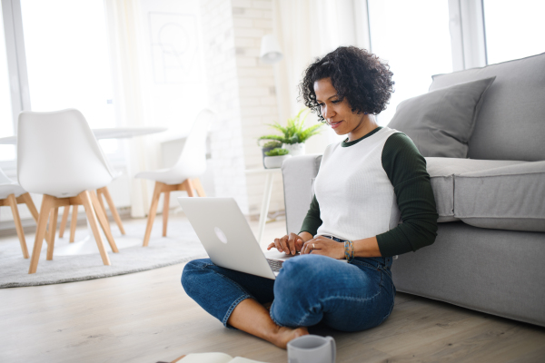 A portrait of happy mature woman working on laptop indoors, home office concept.