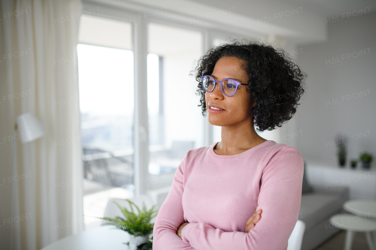 A portrait of happy mature woman indoors at home, looking aside.