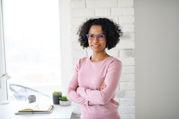 A portrait of happy mature woman indoors at home, looking at camera.