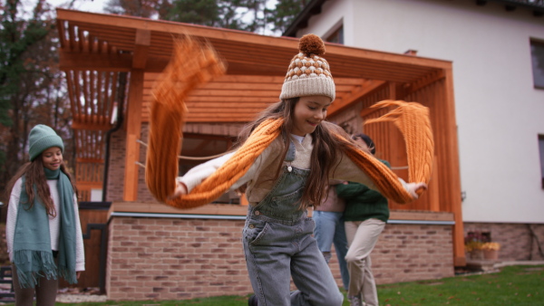 Two happy sisters with a mother and grandmother playing and running outdoors in garden in autumn