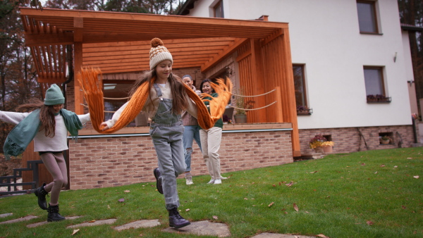 Two happy sisters with a mother and grandmother playing and running outdoors in garden in autumn