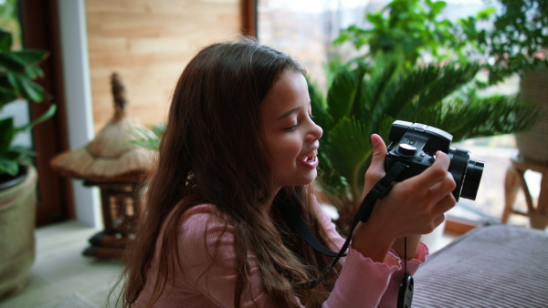 A little girl taking pictures with camera at home.