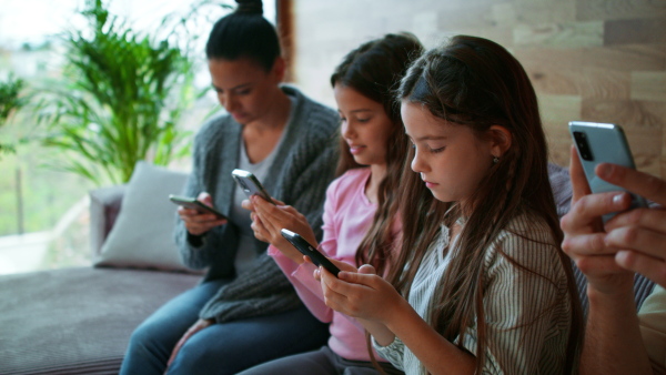 A family with two little daughters, everyone is using mobile phone in the living room.