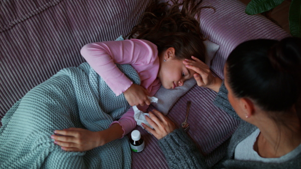 A mother taking care of her sick daughter at home.