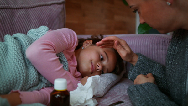 A mother taking care of her sick daughter at home.