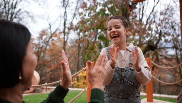 A happy little girl with grandmother playing clapping hands game outdoors in patio in autumn