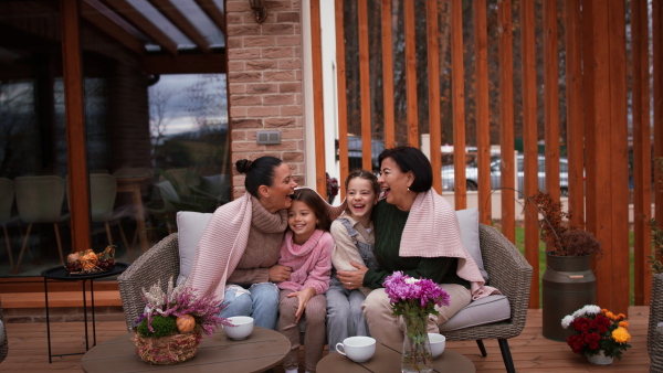 Three generations females sitting outdoors in a patio in autumn