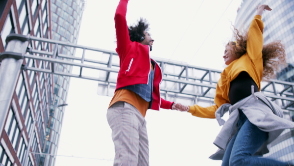 Young couple making video for social media outdoors on street, jumping. Copy space.