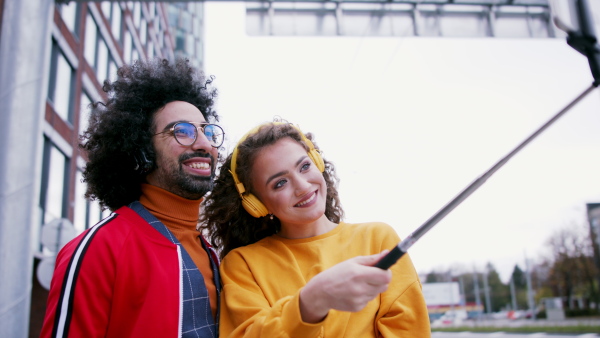 Young couple with smartphone making video for social media outdoors on street.