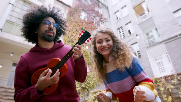 Young couple with guitar making video for social media outdoors on street.