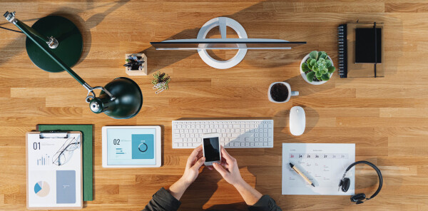 A top view of businessman working on computer at desk with paperwork in home office.